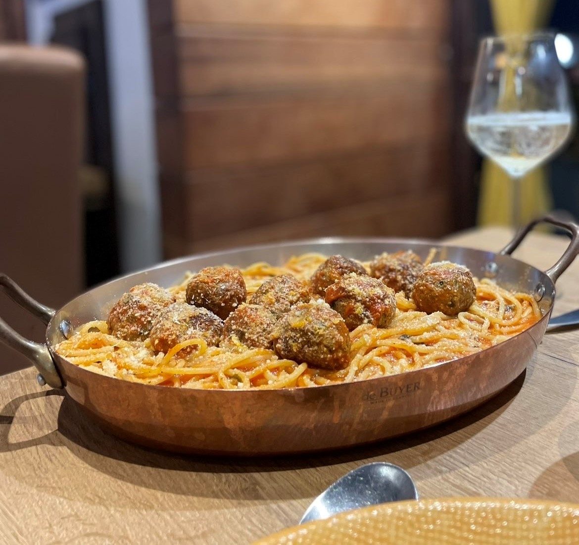 Spaghetti aux boulettes de veau, bœuf et agneau à la sauce tomate maison, servis en plat de cuivre